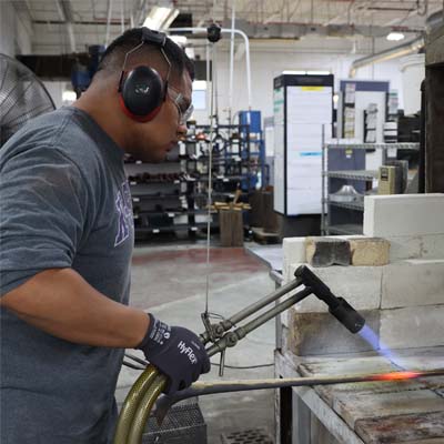 Employee soldering a tube