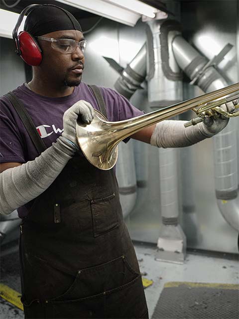 employee buffing a trombone assembly