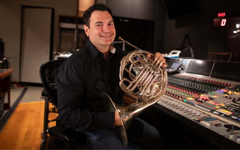 Dylan Skye Hart holding a horn in a recording studio